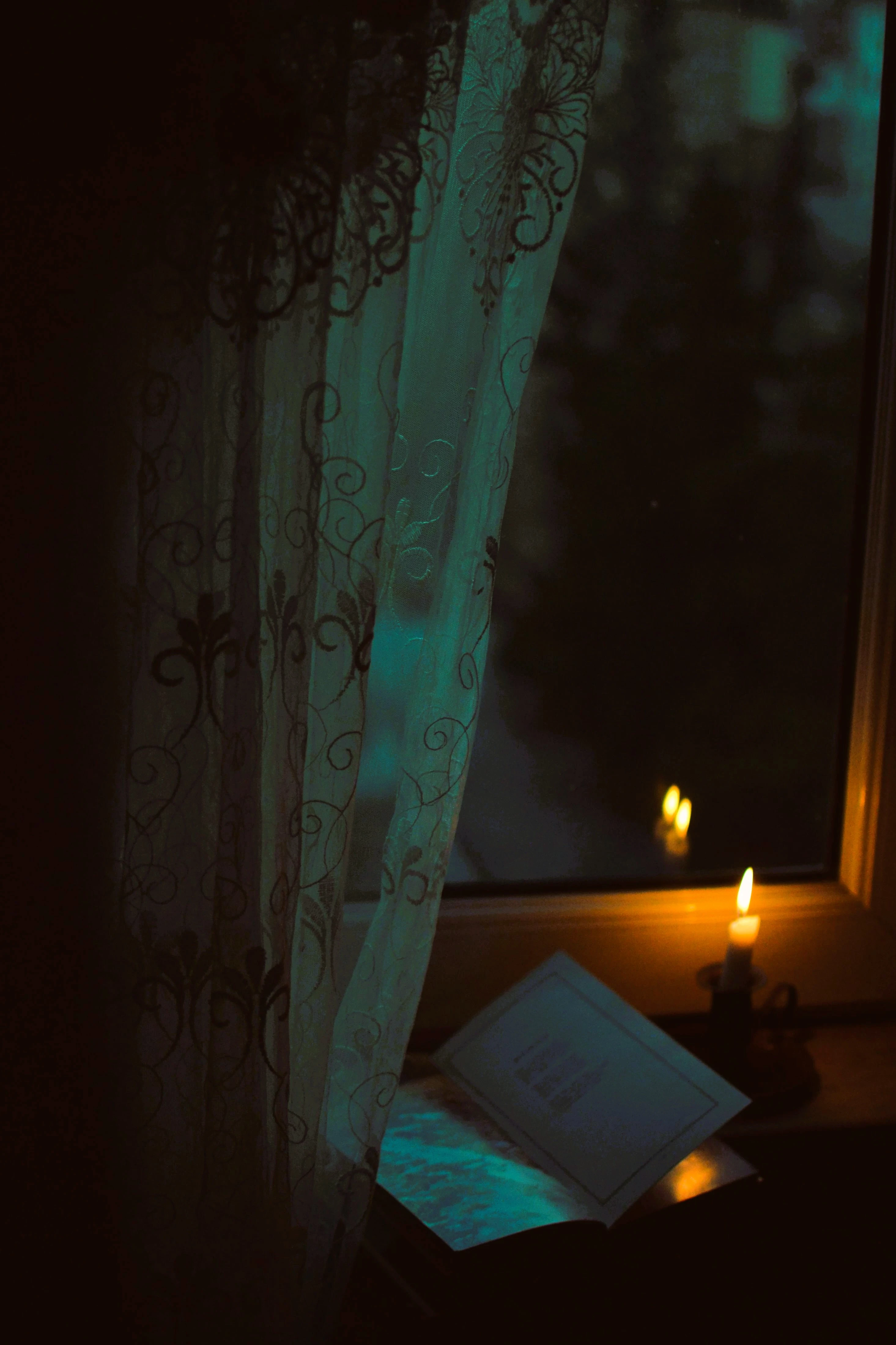 Bougie allumée devant une fenêtre, de nuit